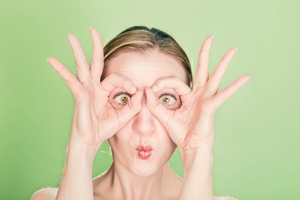 A woman making a glasses face with her hands and eyes